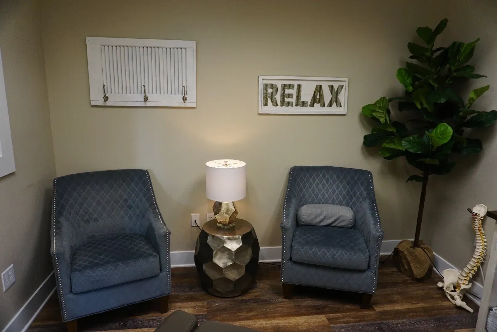 Two blue chairs in a room with the word relax on the wall.