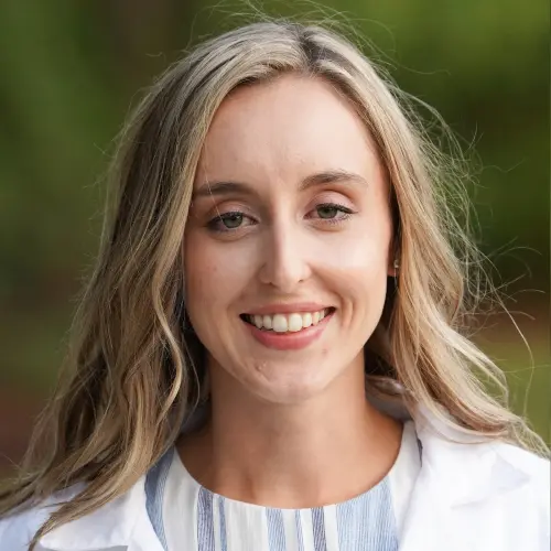 A woman in white lab coat smiling for the camera.