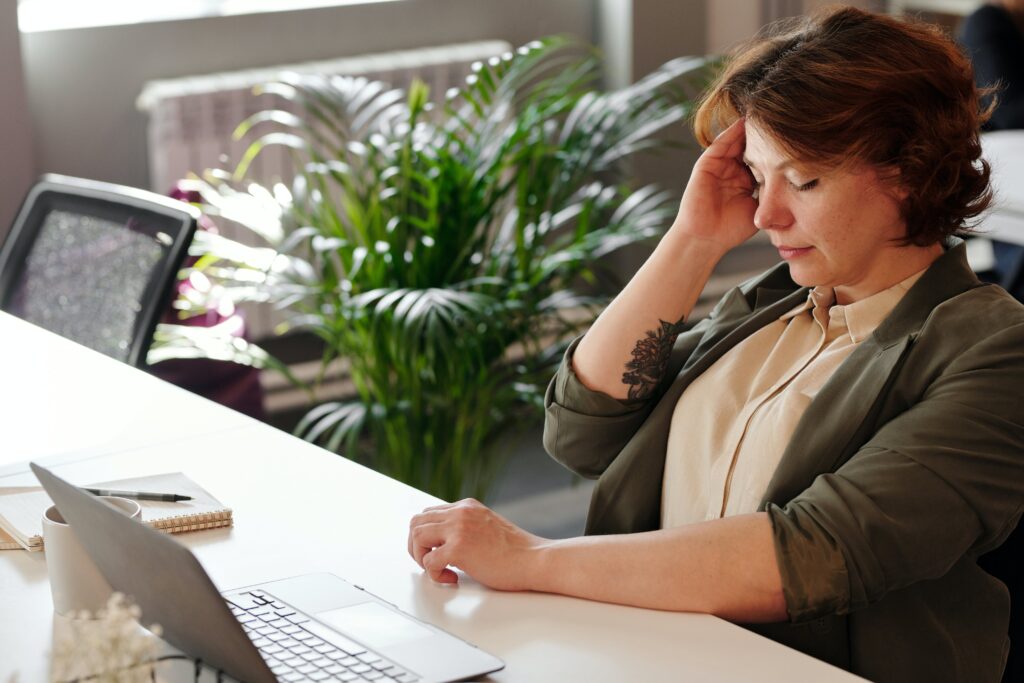 A woman sitting at a table with her hand on the head.